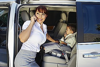 Business woman using mobile phone with son in car