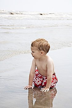 Boy on hands and knees in water from sea