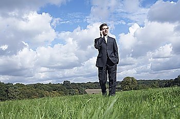 Business man talking on mobile phone in field