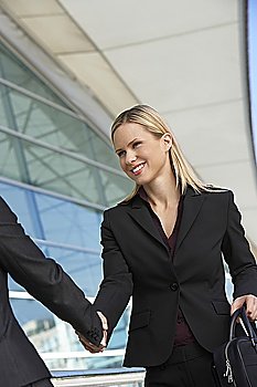 Businesswoman shaking hands with businessman outdoors