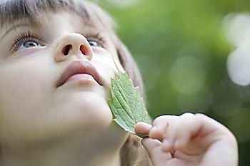 Girl holds leaf to her chin looking up