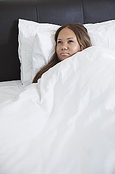 Thoughtful young pregnant woman lying in bed