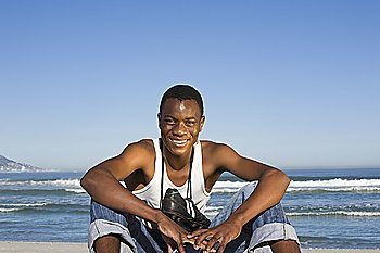 Man sitting on beach with with football boots round his neck