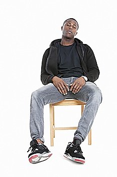 Portrait of a trendy African American man sitting on chair over gray background