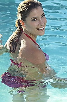 Woman in bikini in water smiling over shoulder, portrait