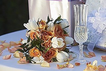 Bouquet, champagne glass and presents on table, close-up