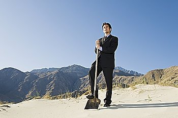 Businessman Holding Spade in the Desert