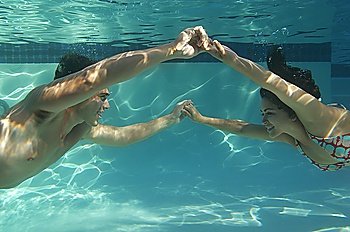 Young couple holding hands in swimming pool underwater
