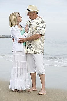 Senior couple stand embracing on beach