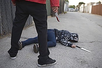 Man standing next to stabbed man lying on ground