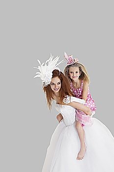 Bridesmaid getting a piggyback ride from young bride over gray background