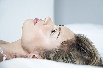 Profile of young woman in underwear lying on bed, close-up
