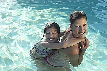 Mother giving daughter piggy back in swimming pool, portrait