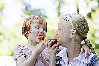 Two girls (3-7) eating fruits, smiling