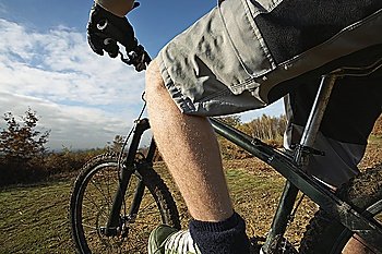 Man riding mountain bike in countryside, mid section