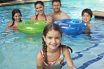 Family with two girls and boy with inflatable rafts, in swimming pool,  portrait