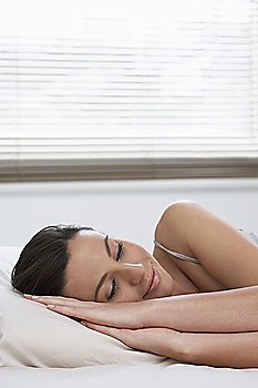 Young woman asleep in bed, smiling