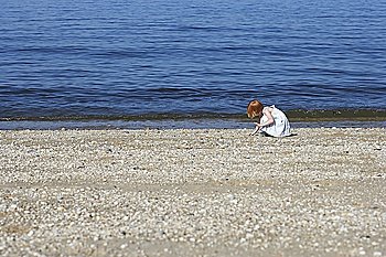 Young girl (5-6) squatting on beach