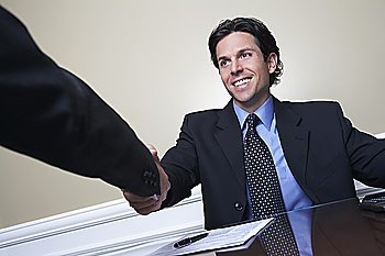 Business man shaking hands with colleague at desk in office