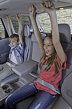 Cheerful children sitting at the back seat of car