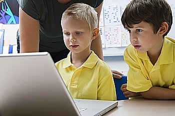 Two schoolboys sit learning computer technology
