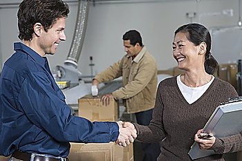Man and woman shaking hands in distribution warehouse