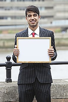Portrait of young Indian businessman holding blank sign