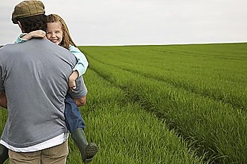 Father embracing daughter (5-6) in field