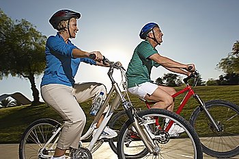 Senior couple cycling in park at dusk