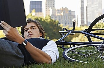 Man lying on lawn, reading book, close-up
