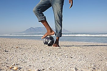 Man´s foot on soccer ball, beach scene
