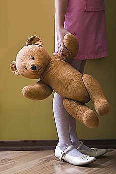 Girl holding teddy bear in home