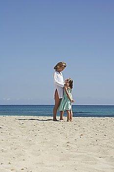 Mother and daughter (5-6) standing face to face on beach