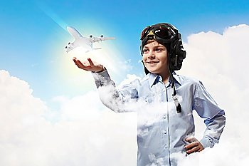 Image of little boy in pilots helmet with toy airplane in hand