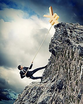 businessman climbing mountain with yen on top