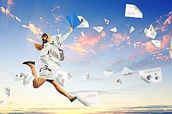 Image of a businesswoman jumping high against blue sky background