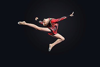 Young cute woman in gymnast suit show athletic skill on black background