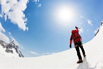 A male mountaineer expresses his joy reaching the summit  of a snowed mountain peak. Mont Blanc, France.