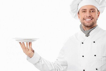 Attractive cook holding an empty plate on a white background