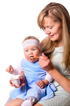 woman is feeding her baby with a spoon