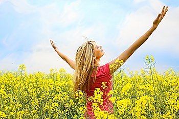 happy blond girl with open arms in a big hug to the sky in a yellow field
