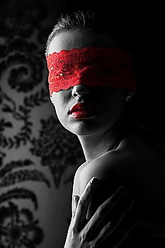 sensual portrait of a young brunette on black background with a red mask of lace