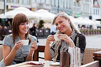 very cute smiling women drinking a coffee sitting outside in a cafe bistro
