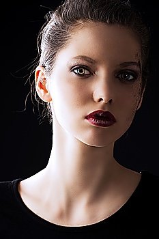 close up portrait of very beautiful young lady actrees over a dark background with dirty make up and fashion light, she is slightly turned of three quarters at left and she looks in to the lens with intense expression
