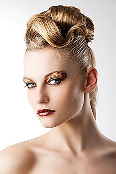 fashion beauty portarit of blond young cute girl with creative hair style and leopard make up, she is turned of three quarters at right and looks in to the lens