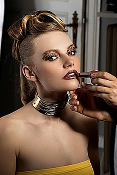 fashion portrait of cute and elegant lady doing make up on backstage with spot light on her face