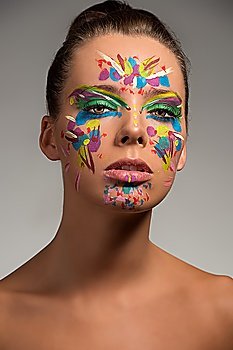 pretty girl with abstract make-up on the face, she is in front of the camera and looks in to the lens
