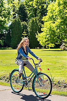 Girl enjoying summer break riding bicycle in the park