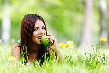 Woman with apple laying on green grass