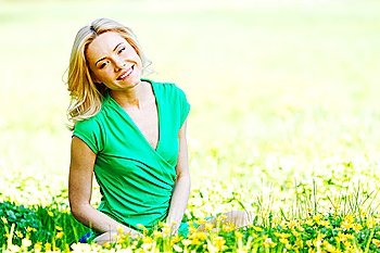 Beautiful young woman sitting on flower field